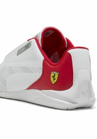 Bijele i crvene tenisice s glatkim sintetičkim gornjim dijelom, perforiranim detaljima, srebrnim detaljem i malim Ferrari logom na peti.