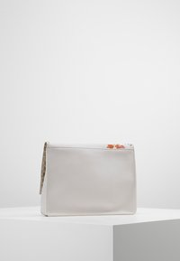 Vit läderhandväska med rektangulär form, texturerad yta och blommotiv längs den övre kanten. Har en dragkedjestängning och guldstift.