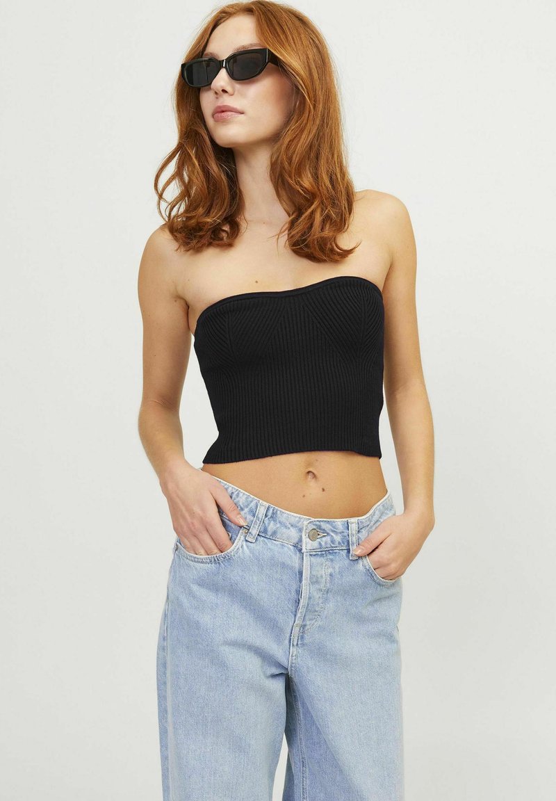 Zwarte geribbelde strapless top met een aansluitend ontwerp, gecombineerd met lichtblauwe hoge taille spijkerbroek. Minimale hardware en naadloze textuur.