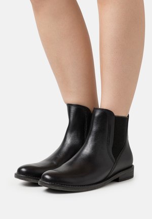 Schwarze Leder-Stiefeletten mit elastischen seitlichen Einsätzen, runder Spitze, niedrigem Absatz und genähtem Detail an der Sohle. Glatte Textur.