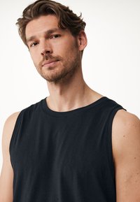 Svart ärmlös skjorta i mjukt tyg, med rund halsringning och avslappnad passform. Slät yta utan synliga mönster eller detaljer.