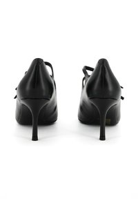 Scarpe con tacco alto nere in pelle, con punta affusolata, tacchi sottili e cinturini alla caviglia. Texture liscia con elementi di design minimalisti.