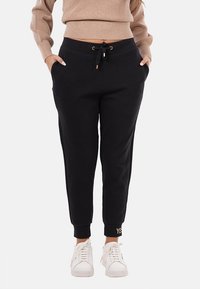 Pantaloni da tuta neri con vita regolabile, orli a costina e tasche laterali. Presentano la scritta "YES" ricamata in oro sul risvolto sinistro.