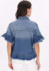 Jeansjacka med korta, fransade ärmar och en volangkant, med en medelblå tvätt och en klassisk kragsdesign.