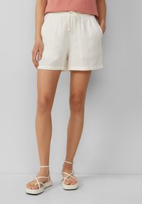 Shorts en coton blanc avec une taille élastique, cordon de serrage et poches latérales ; texture douce, ourlet à revers, longueur mi-cuisse.