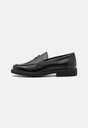 Black leather loafer with a low heel, rounded toe, and a strap across the upper, shown against a plain background.
