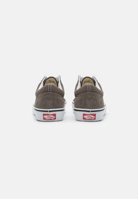 Braune Wildledersneaker mit weißen Sohlen, gepolstertem Kragen, kontrastierenden Nähten und einem roten "Vans Off the Wall"-Logo an der Ferse.