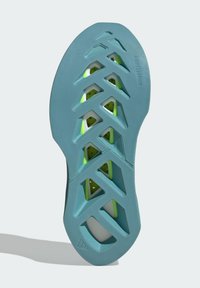 Sole topánky v svetlomodrej farbe s textúrovaným povrchom. Obsahuje trojuholníkové výrezy a neonovo zelené akcenty pre lepšiu priľnavosť a flexibilitu.
