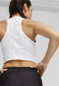 Hvid, ærmeløs sports crop top med et tekstureret mønster, parret med sorte højtaljede leggings med en glat talje.