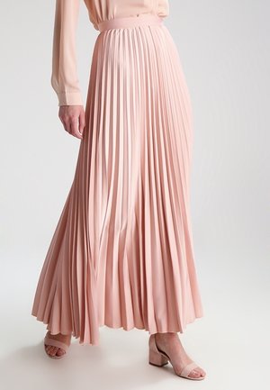 Pehmeän vaaleanpunainen laskostettu maksihame, jossa on korkea vyötärökaitale, virtaava muotoilu ja sileä pinta, yhdistetty vaalean sävyisiin korkokenkiin.