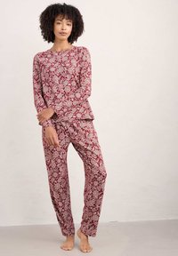 Conjunto de ropa de estar en casa con estampado floral en burdeos y crema, que incluye mangas largas, pantalones de corte suelto y una tela suave y texturizada.