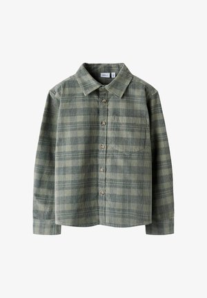Chemise en flanelle à carreaux verts avec col boutonné, manches longues et poche poitrine ; présente un tissu texturé et un motif à carreaux prononcé.