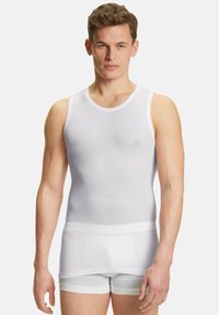 Top bianco senza maniche realizzato in tessuto elasticizzato, con scollatura rotonda e texture a coste, indossato su pantaloni corti bianchi. Design pulito e semplice.