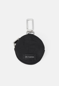 Czarna, pikowana, okrągła saszetka uszyta z materiału, z srebrnym klipsem i zamkiem błyskawicznym. Czarna metka z białym napisem brzmi "ŻYCIE JEST WSPANIAŁE."
