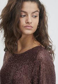 Top en sequins marron avec un col rond, tissu texturé et manches courtes, doté d'une coupe slim et d'une surface scintillante.