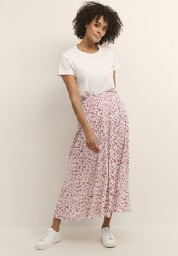 Floral maxi skirt in white with pink and green patterns, featuring a gathered waistband, paired with a plain white t-shirt and white sneakers.