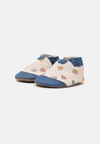 Zapatos suaves de color crema con acentos azules, que presentan un patrón de peces juguetones. Fabricados con material flexible, con una suela adaptable para mayor comodidad.