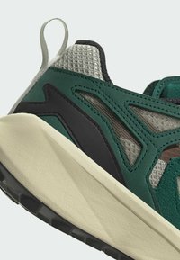 Sneaker in tessuto verde con tomaia in rete, dettagli in gomma, finiture testurizzate e suola chunky bianca sporca con battistrada nera.