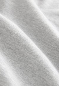 Pilka medvilninė medžiaga su lygiu paviršiumi, turinti subtilių atspalvių variacijų ir smulkių, tankiai susiūtų siūlų. Minkštas, lankstus kritimas.