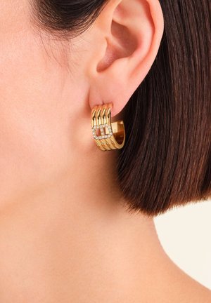 Boucle d'oreille créole en or avec un design texturé et cinq rainures horizontales. Comprend un accent carré orné de cristaux clairs pour plus de détails.