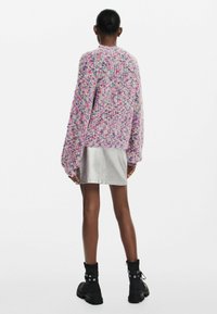 Tömény kötésű pulóver pasztell színekben, laza szabással, fémes ezüst szoknyával és fekete bokacsizmával ezüst részletekkel párosítva.