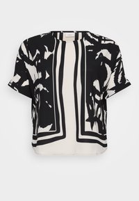 Blusa a maniche corte in bianco e nero con modelli astratti audaci, scollo rotondo e vestibilità ampia con bordi a contrasto.