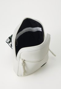 Sacchetto in tessuto bianco con una superficie liscia, chiusura a zip e un interno nero caratterizzato da una striscia bianca orizzontale nella parte superiore.