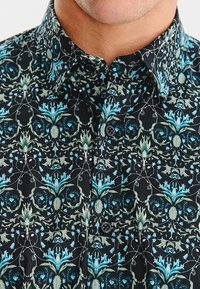 Czarna koszula z guzikami z detailed floral pattern w odcieniach niebieskiego i zielonego. Gładka tekstura, klasyczny kołnierzyk oraz guziki z przodu.