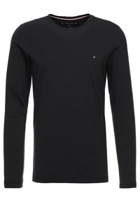Mustassa pitkähihaisessa T-paidassa on pyöreä kaulus, slim fit -malli ja pieni brodeerattu logo rinnassa. Sujuva materiaali.