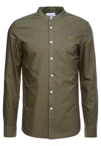 Zielona oliwkowa koszula z długim rękawem, stojącym kołnierzem, zapięciem na guziki z przodu i białymi guzikami. Na piersi znajduje się żółte haftowane logo.