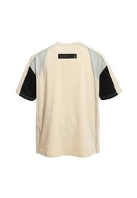 Camisa de manga corta en algodón beige, con acentos en negro y gris. Incluye una etiqueta negra en la parte superior de la espalda y costuras en contraste.