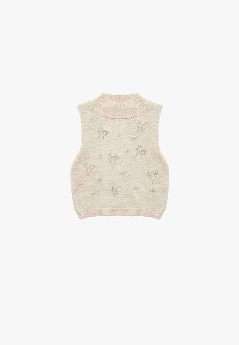 Maglioncino senza maniche di un beige chiaro con collo alto, caratterizzato da motivi decorativi ricamati di fiocchi e stelle su tutta la superficie.