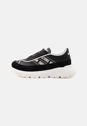 Baskets à plateforme noir et blanc avec semelle blanche épaisse, bordure en daim noire et motif texte blanc sur le côté indiquant "Moschino."