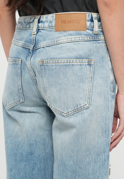 Lichtblauwe denim jeans met een relaxed fit, voorzien van een bruine leren label op de tailleband en twee achterzakken met gestikte details.