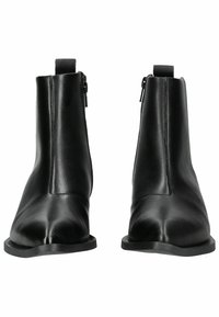 Bottes chelsea en cuir noir avec une finition lisse, bout pointu et zips sur les côtés. Elles disposent d'une semelle en caoutchouc plate et d'un design minimaliste.