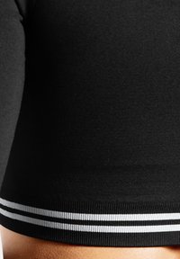 Sort cropped top med en glat tekstur, der har en ribbet kant og to vandrette hvide striber som accentdetalje.