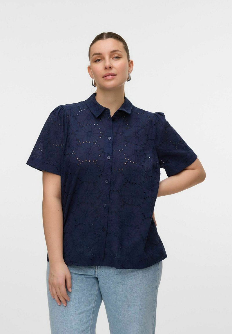 Camicia blu navy a maniche corte con motivo a occhiello floreale, apertura frontale con bottoni e maniche leggermente a sbuffo. Abbinala a denim azzurro chiaro.