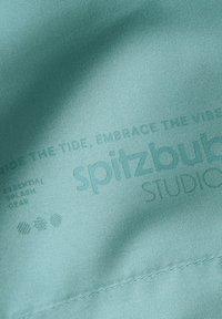 Lichtblauwe stof met reliëftekst: "spitzbub STUDIOS" en zinnen "CATCH THE TIDE, EMBRACE THE VIBE." Soepele textuur.