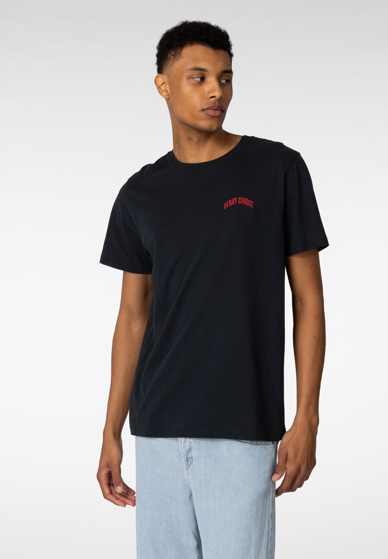 Svart bomull t-skjorte med en rød brodert logo "HENRY CHOICE" på venstre bryst. Rund hals, korte ermer og avslappet passform.