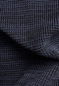 Temně modrá texturovaná látka s pleteným vzorem a výraznými úplety, které vytvářejí žebrovaný vzhled. Měkká a pružná textura.