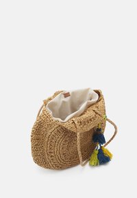 Sac à main en paille tissée avec un motif circulaire, doublure en tissu crème et accent en pompons bleus, jaunes et blancs. Doté de deux poignées tressées.