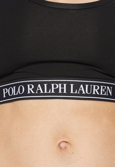 Black ribbed crop top featuring a white logo band with "POLO RALPH LAUREN" text. The texture is smooth, with a fitted design.