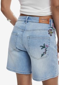 Jeansshorts i ljusblått med blommig brodyr på fickorna, läderpatch med varumärke och klassisk fem-ficksstil.