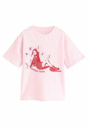 Rožinė medvilninė marškinė su trumpomis rankovėmis, ant kurių pavaizduota raudona mergaitės grafika ir užrašas "mergaitė, kuria visada buvau" su žvaigždžių akcentais.