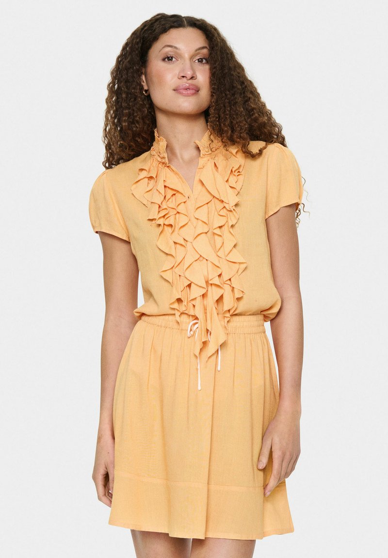 Korte mouw, gerimpelde jurk van zacht oranje stof met een trekkoord in de taille, met een knoopsluiting aan de voorkant en textuurdetails.
