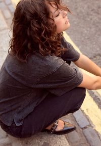 Camicia nera a maniche corte con motivo a diamante caratterizzata da piccoli dettagli, abbinata a pantaloni scuri e scarpe lucide a punta.