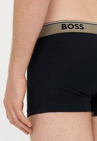 Μαύρα βαμβακερά μποξεράκια με μπεζ ελαστική μέση. Αρχικά "BOSS" στη μέση με μαύρο χρώμα. Ομαλή υφή, εφαρμοστό σχέδιο.