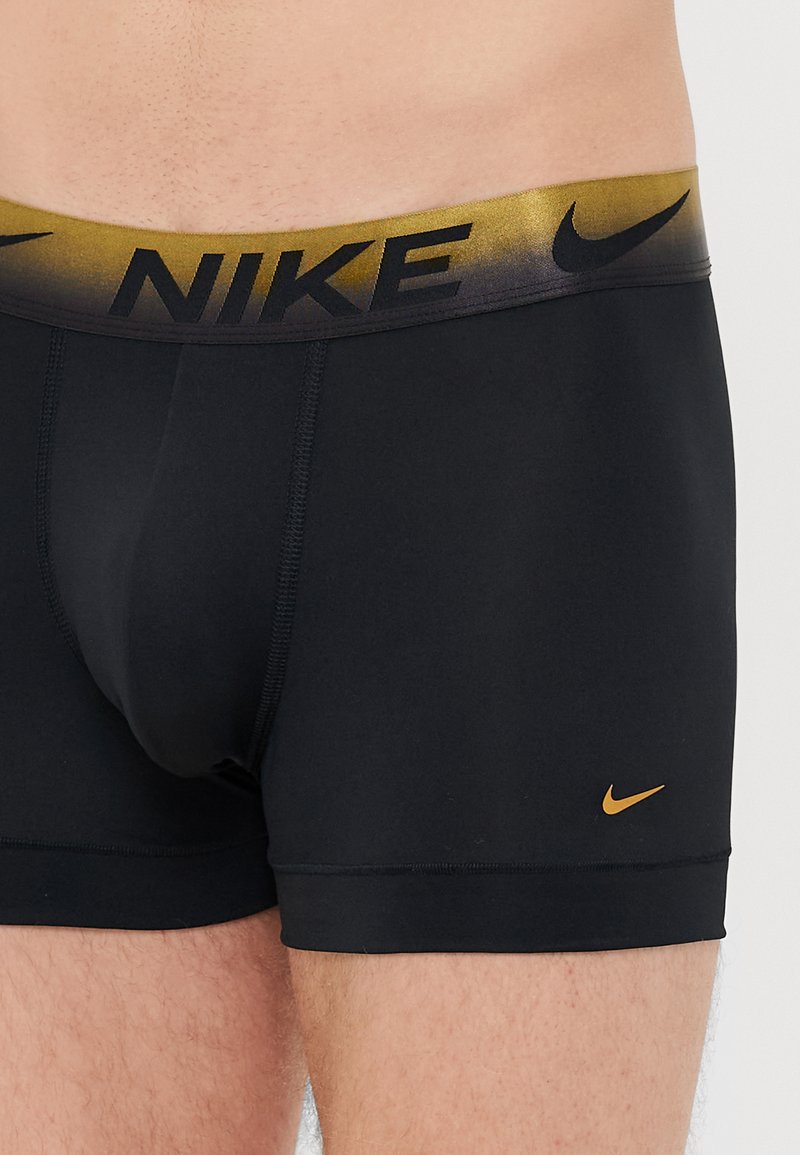 Czarne sportowe bokserki z gradientowym pasem w odcieniach złota, z czarnym logo i detalami przeszyć. Miękki, elastyczny materiał.