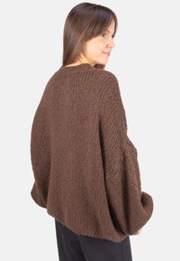 Brauner, übergroßer Strickpullover mit strukturierter Oberfläche und überschnittenen Schultern, der eine weite, lockere Passform und ein Rundhalsausschnitt-Design aufweist.