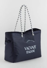 Tote bag tummansininen valmistettu kestävästä kankaasta, jossa on valkoiset köysikahvat ja painettu teksti "VACANZE ITALIANE" ja "YACHTING CLUB."